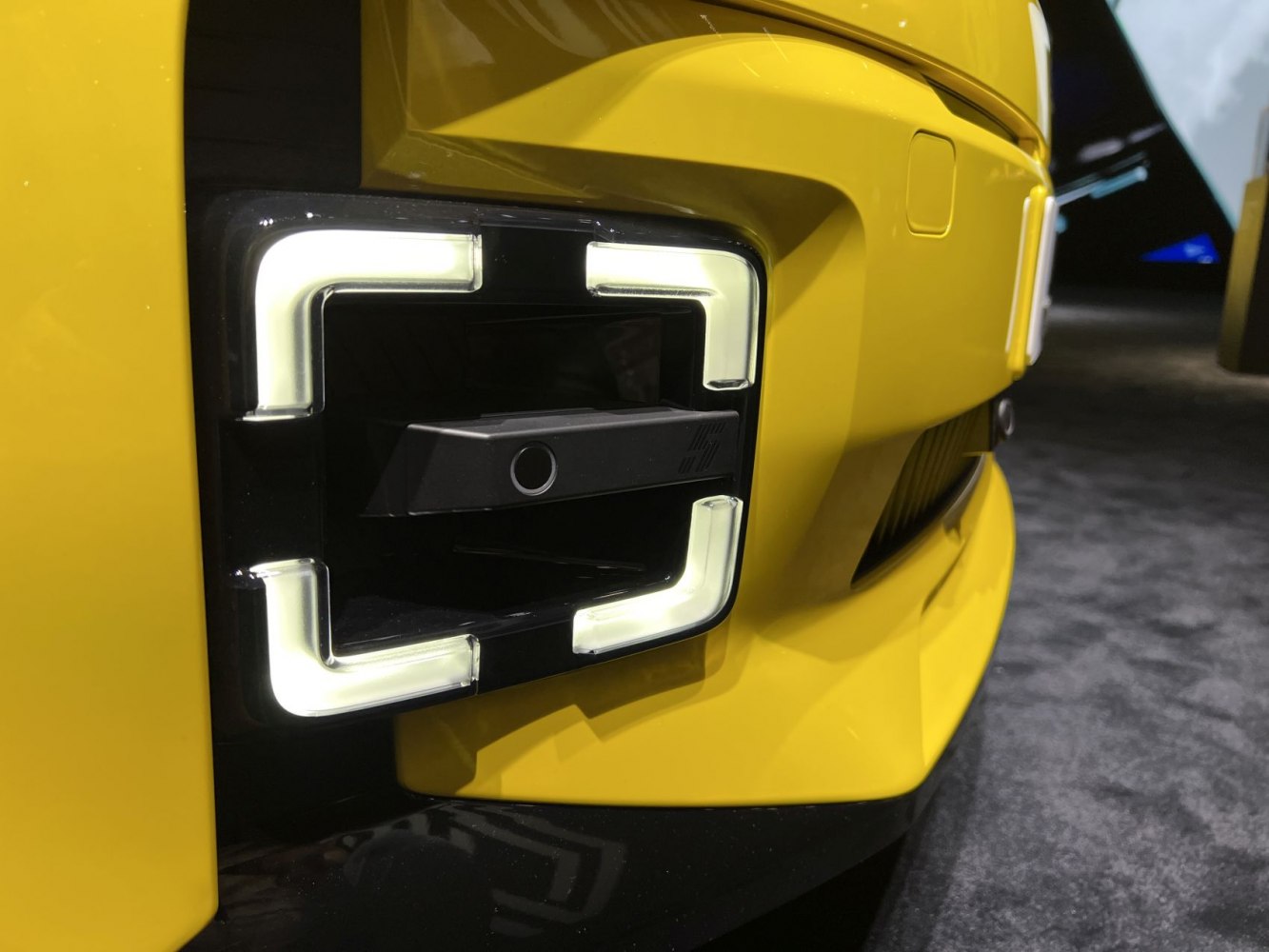 Close-up of front left LED fog light with sensor on a yellow bumper