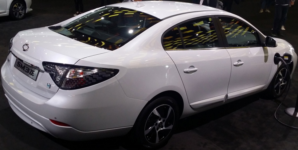 Rear side view of white electric sedan with charging port and sleek design