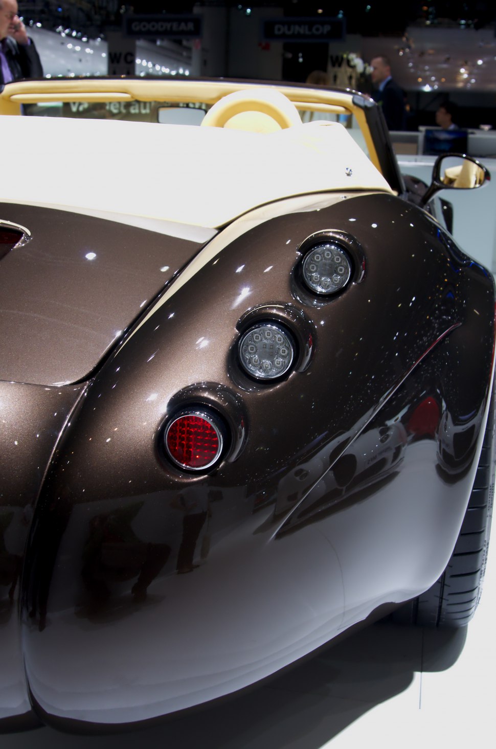 Triple round rear lights on a curved vehicle rear end.