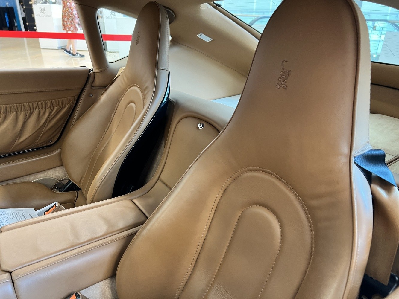 Beige leather luxury sports car seats with unique stitching and headrests.