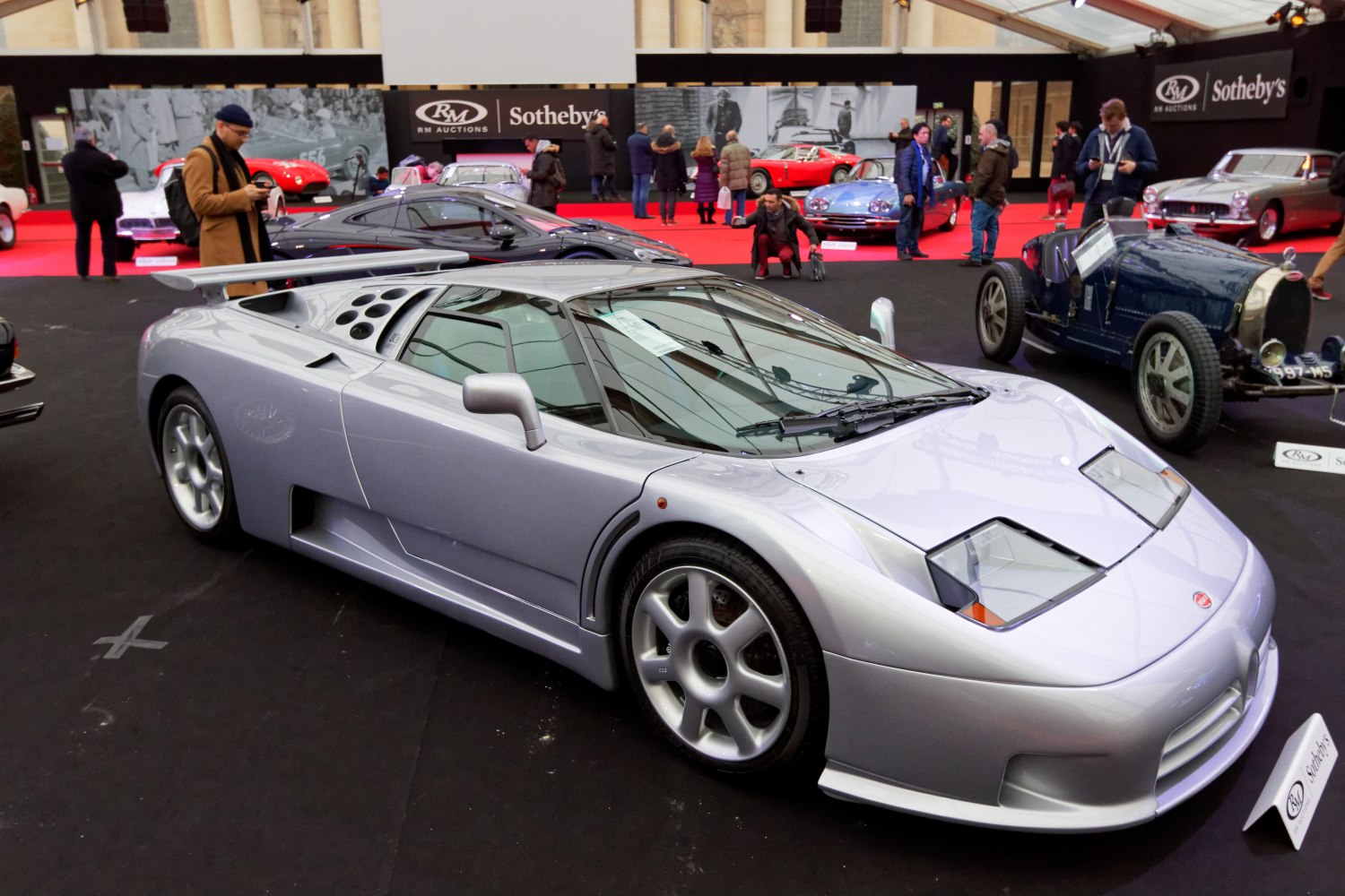Silver mid-engine sports coupe with pop-up headlights and rear wing
