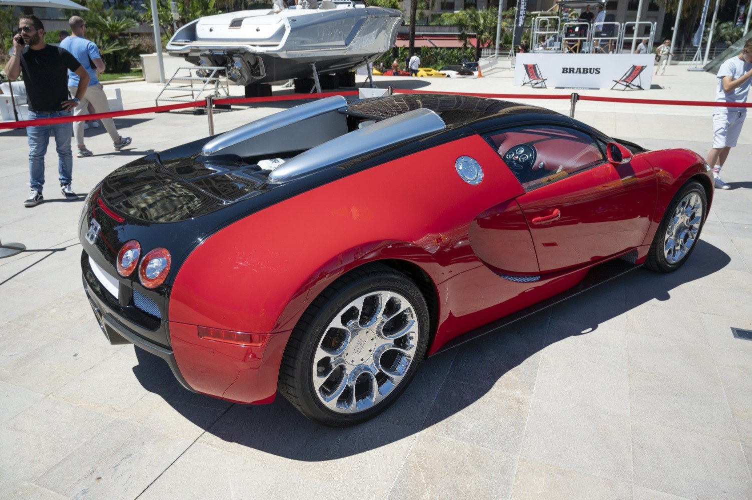 Rear side view of a red and black open-top supercar with alloy wheels.