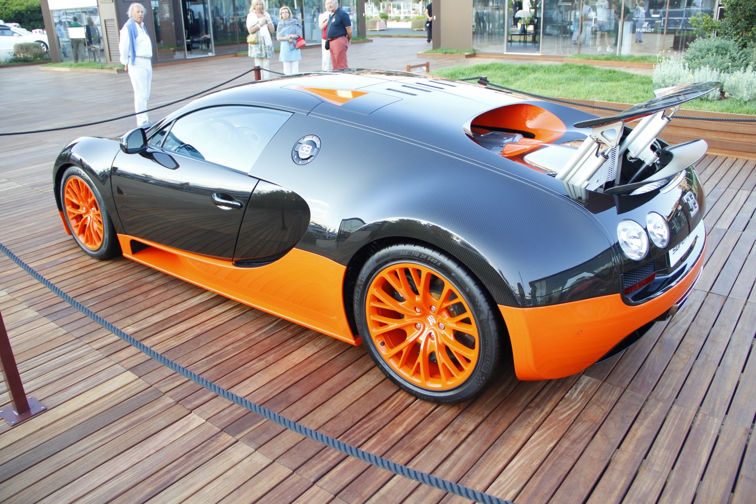Side and rear view with carbon fiber body, orange wheels, raised rear spoiler