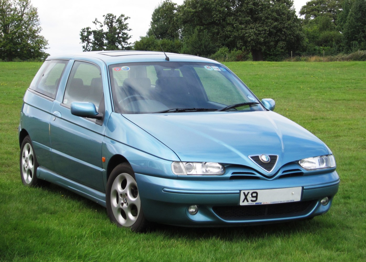 Front view of blue hatchback with triangular grille and sleek headlights