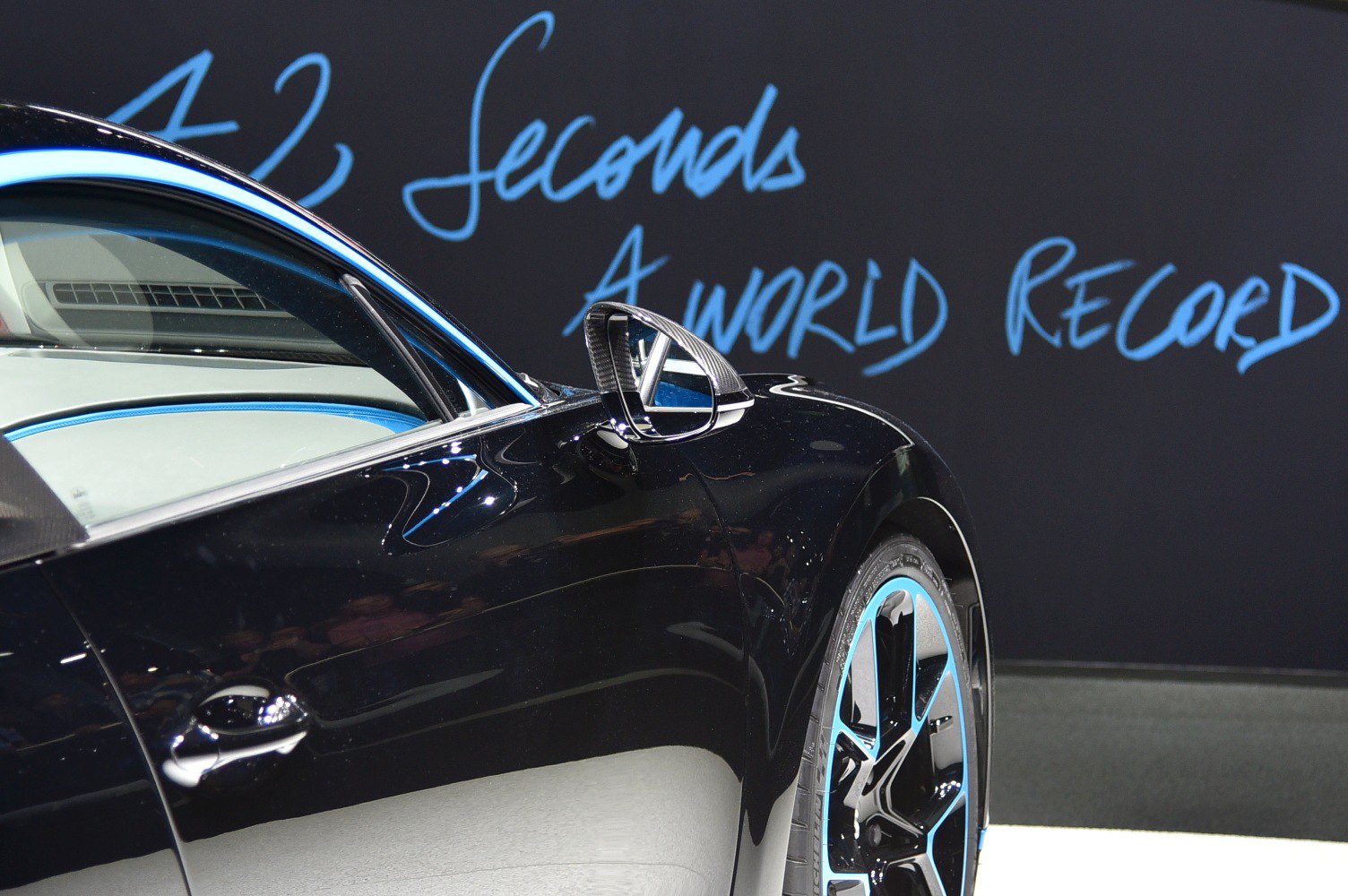 Black car side with blue accents and carbon fiber mirror.