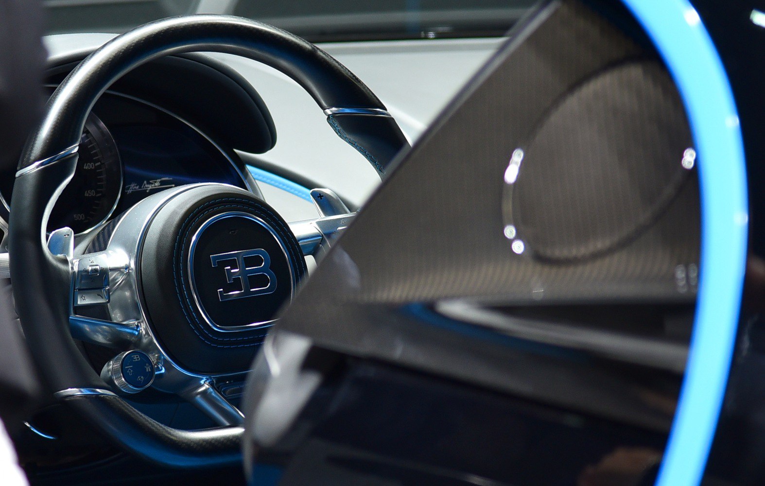 Luxury sport car steering wheel with logo and door speaker close-up