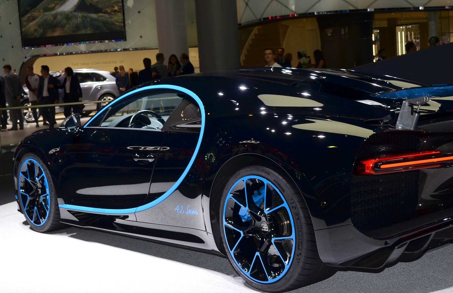 Rear side profile with distinctive blue-accented wheels and aerodynamic body curves