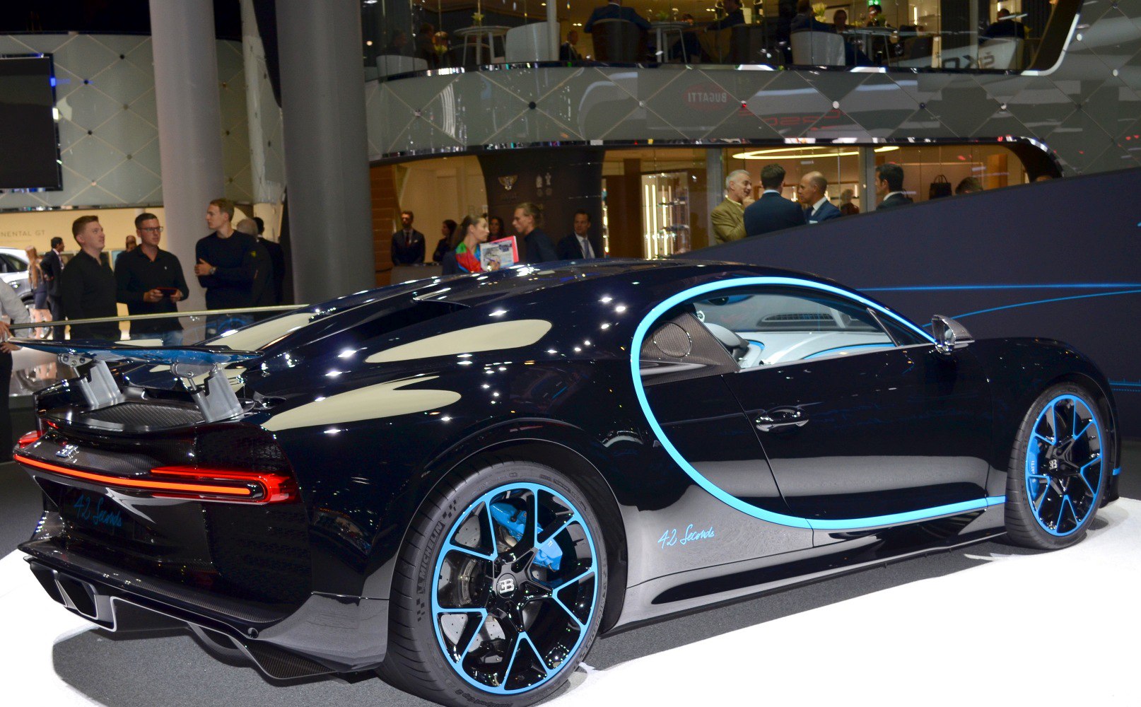 Side and rear view of sleek black hypercar with blue accents and spoiler.