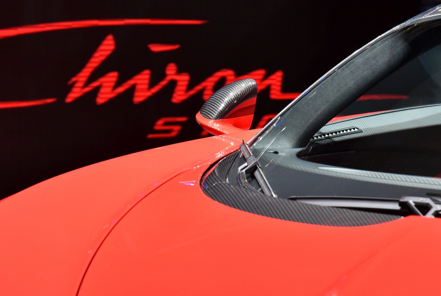 Carbon fiber side mirror and windshield wiper on red supercar hood