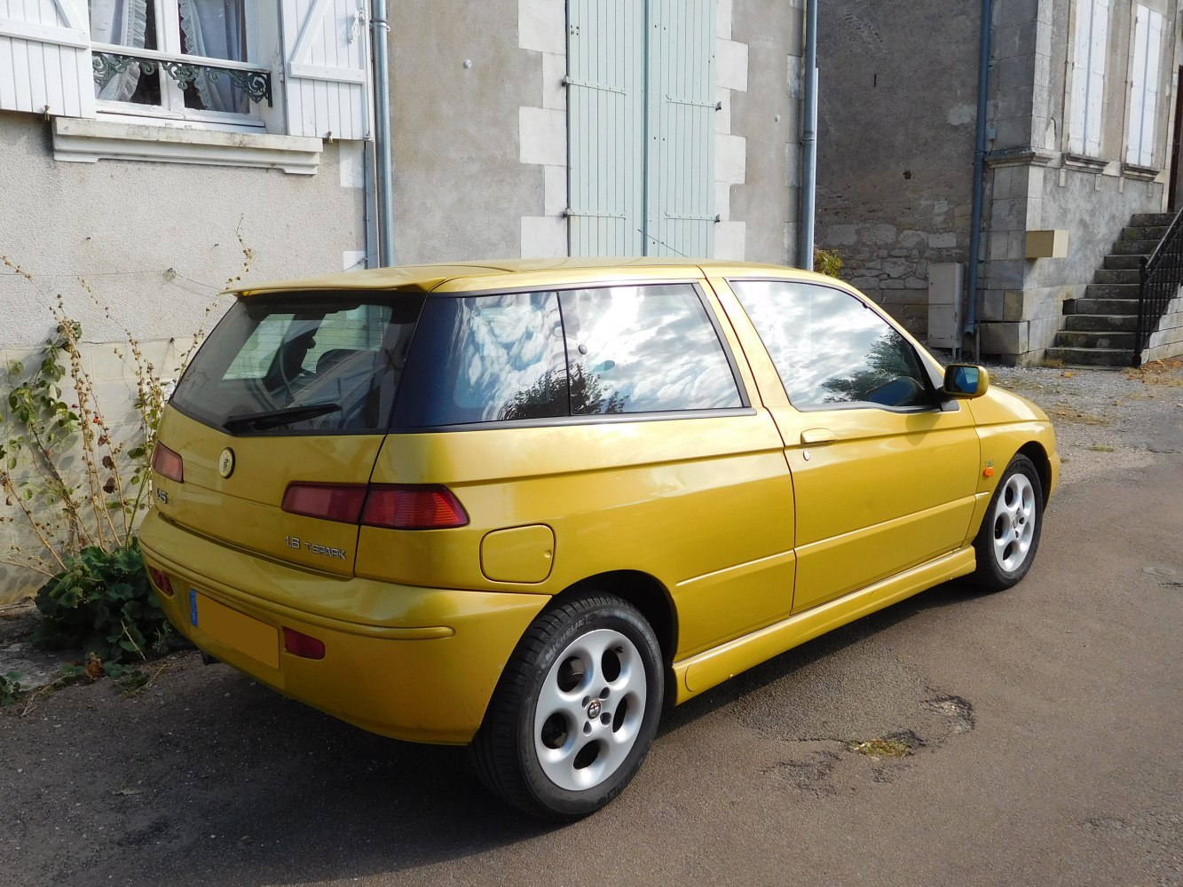 Yellow hatchback rear side view with distinctive taillights and alloy wheels