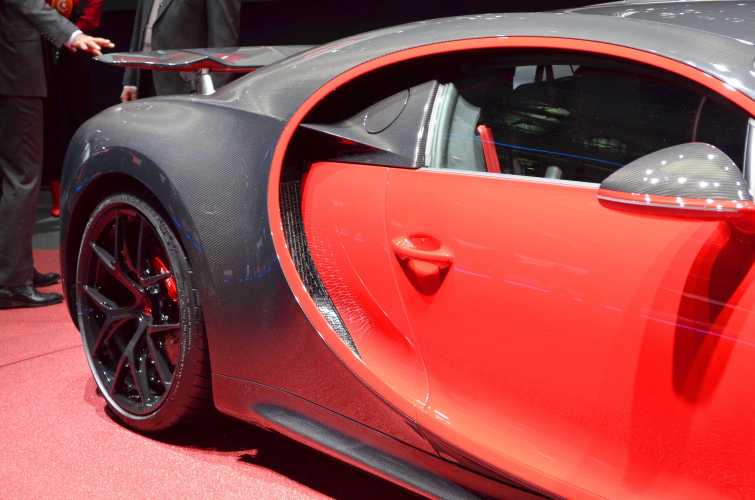 Close-up of carbon fiber body and red door with rear wheel.