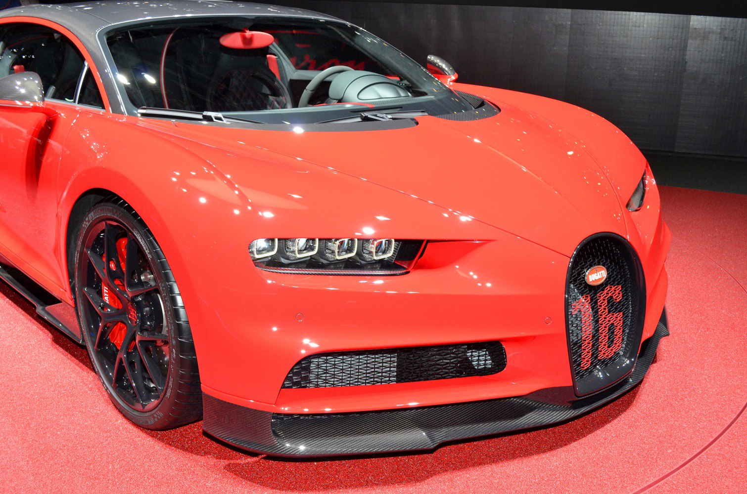 Red sports car front with quad LED headlights and distinctive grille with number 16