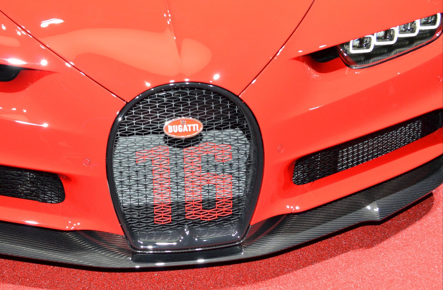 Close-up of front grille and LED headlights with honeycomb mesh and carbon splitter