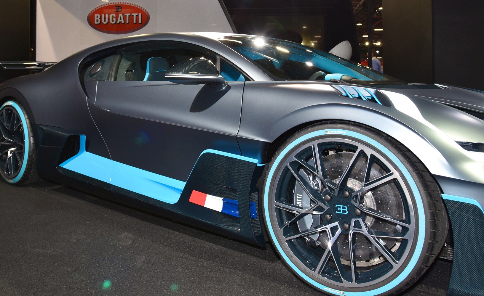 Close-up of a sports car's side profile and blue-accented alloy wheel.