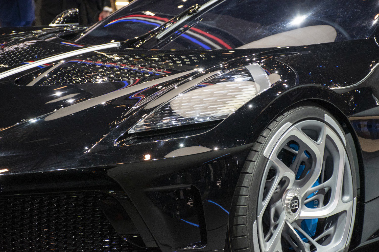 Close-up of front headlight and wheel with alloy rim and tire tread