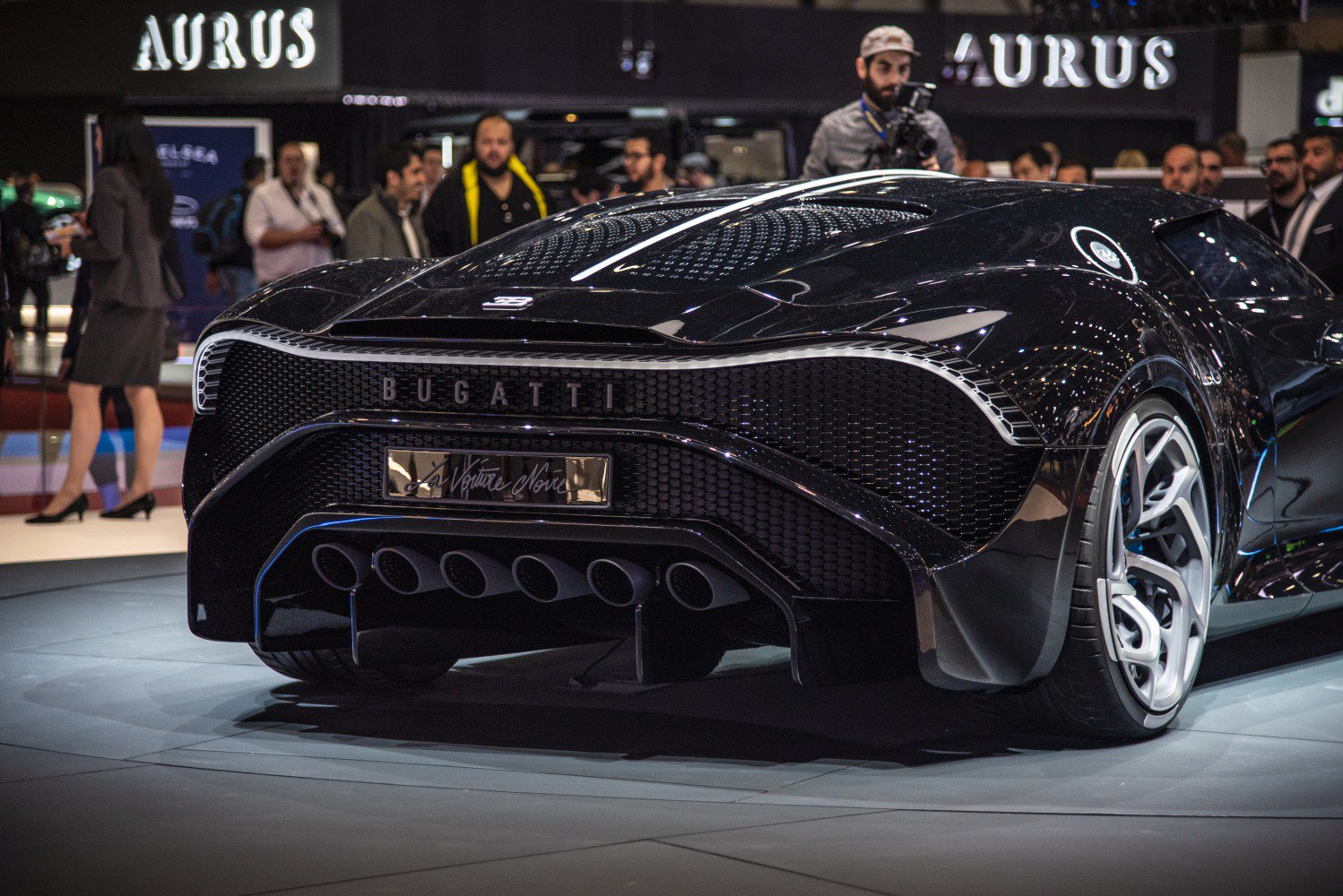 Rear view of a luxury supercar showing six tailpipe exhausts and stylish rear wheel.