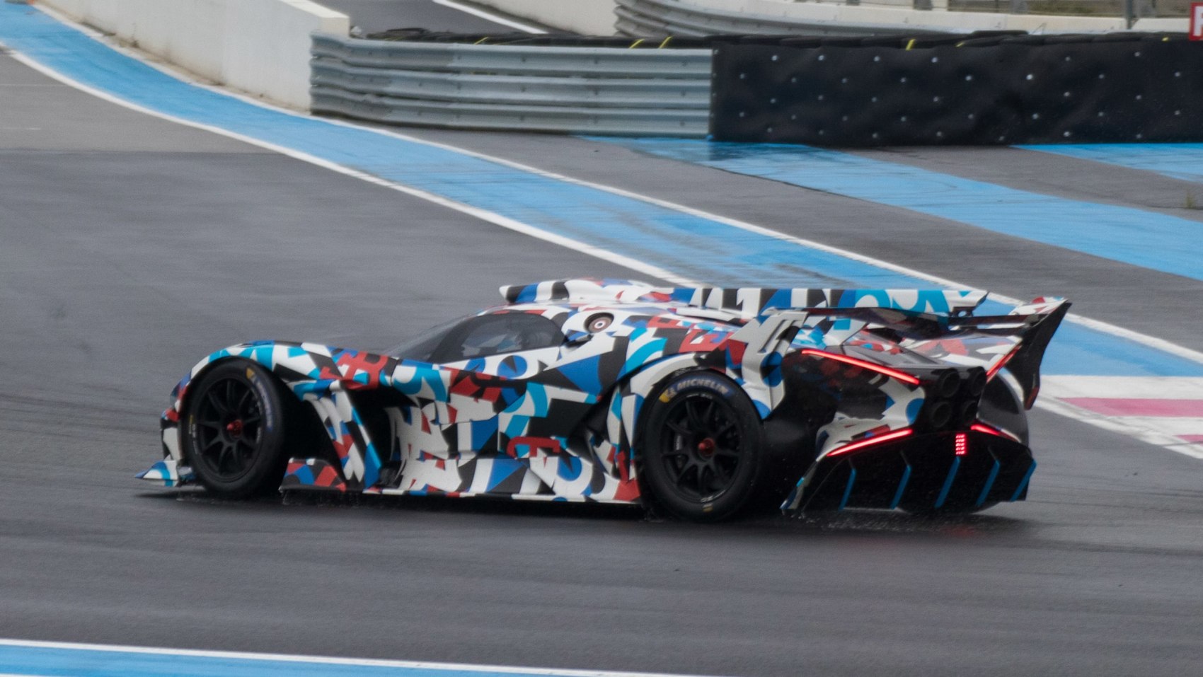 Hypercar with aerodynamic design and vibrant camouflage livery on race track