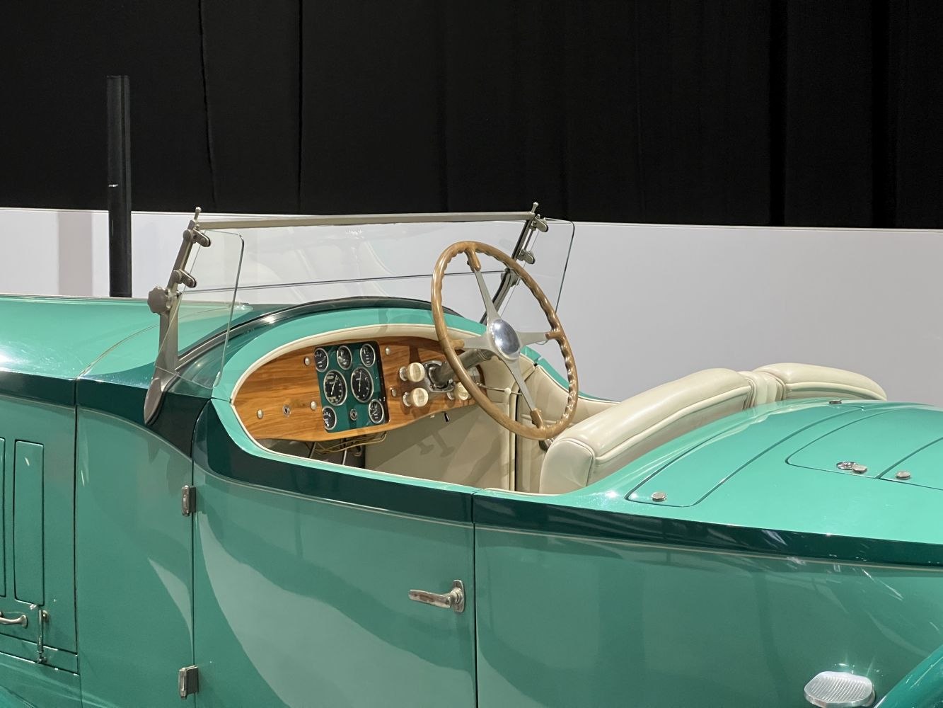Classic vintage open-top roadster interior with wood dashboard and large steering wheel