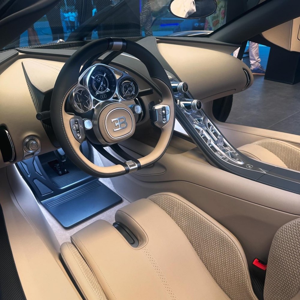 Steering wheel with multiple dials and sleek center console in luxury car interior.