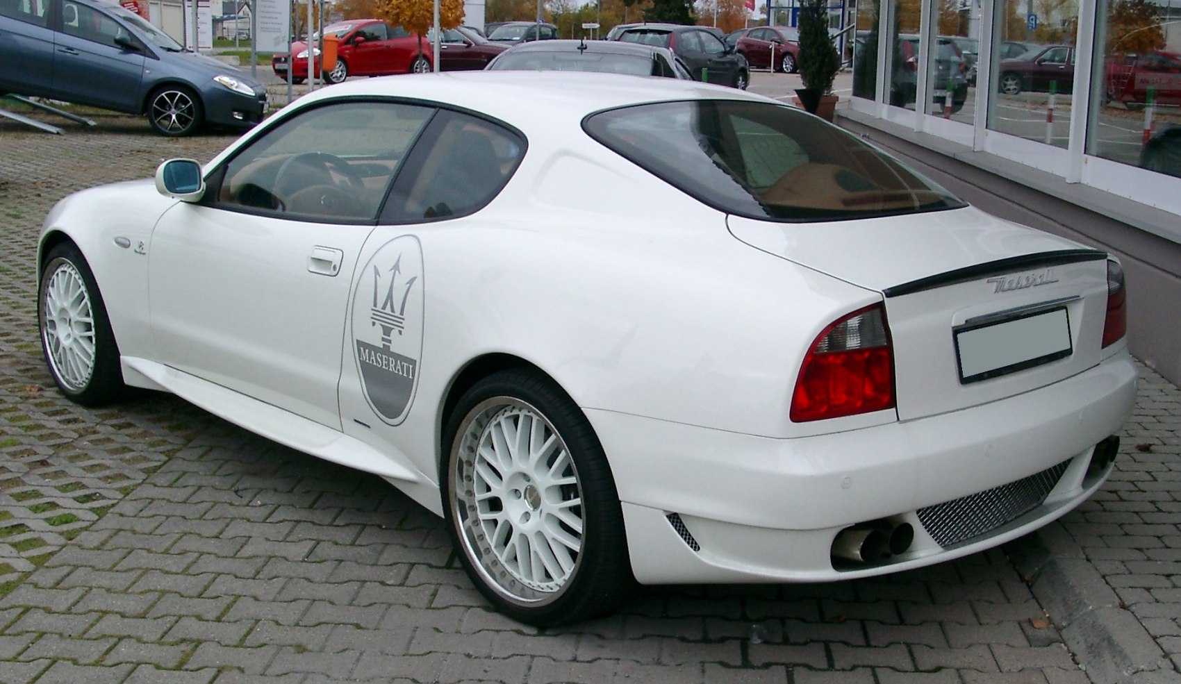 Rear and side view of a white coupe with sporty wheels and distinctive tail lights