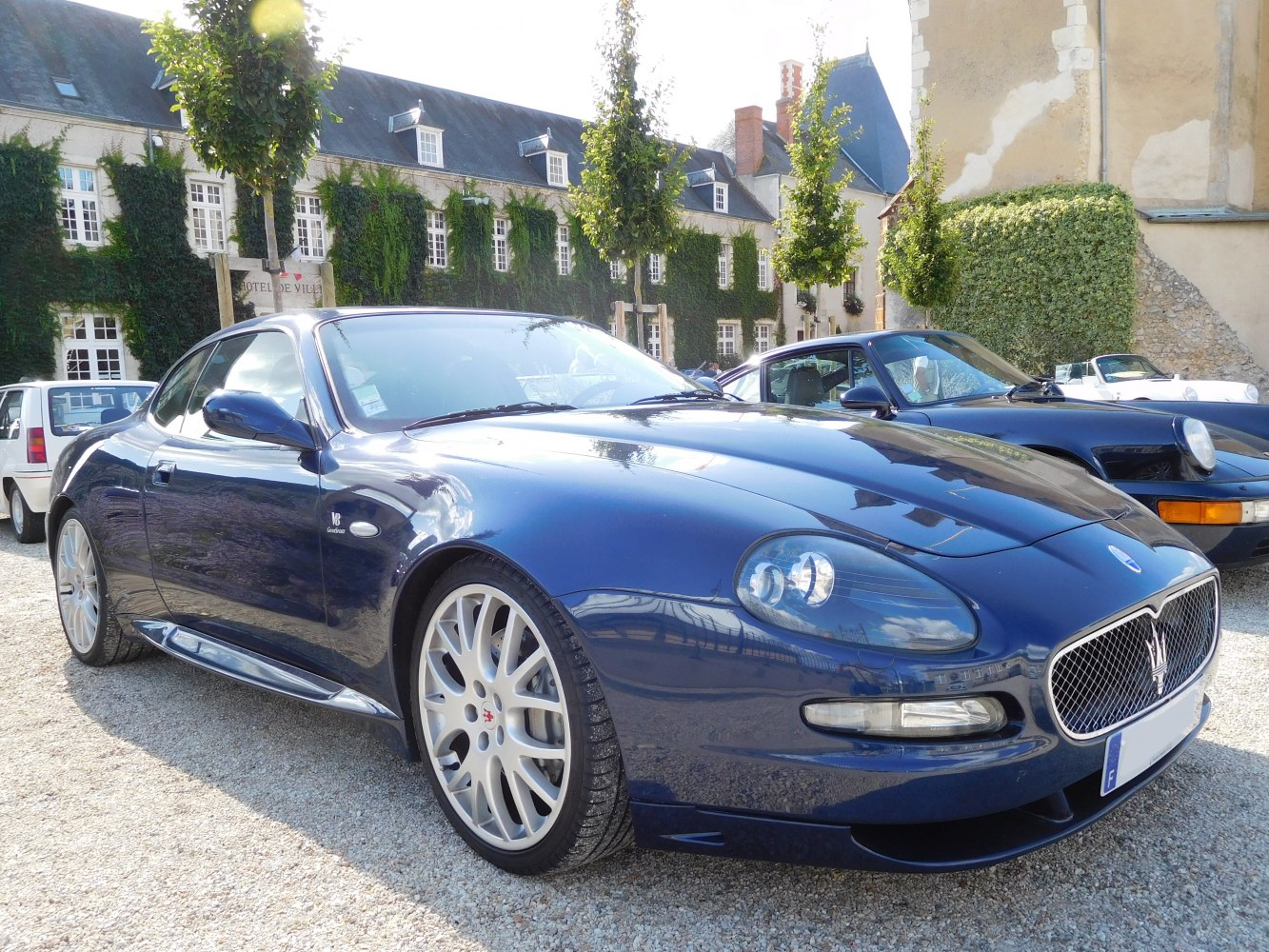 Blue coupe with V8 badge, mesh grille, and alloy wheels.
