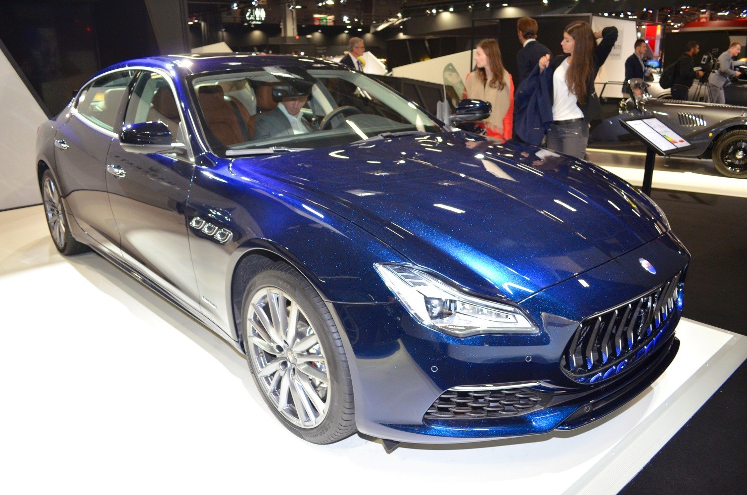 Blue luxury sedan front left with aggressive grille and LED headlights