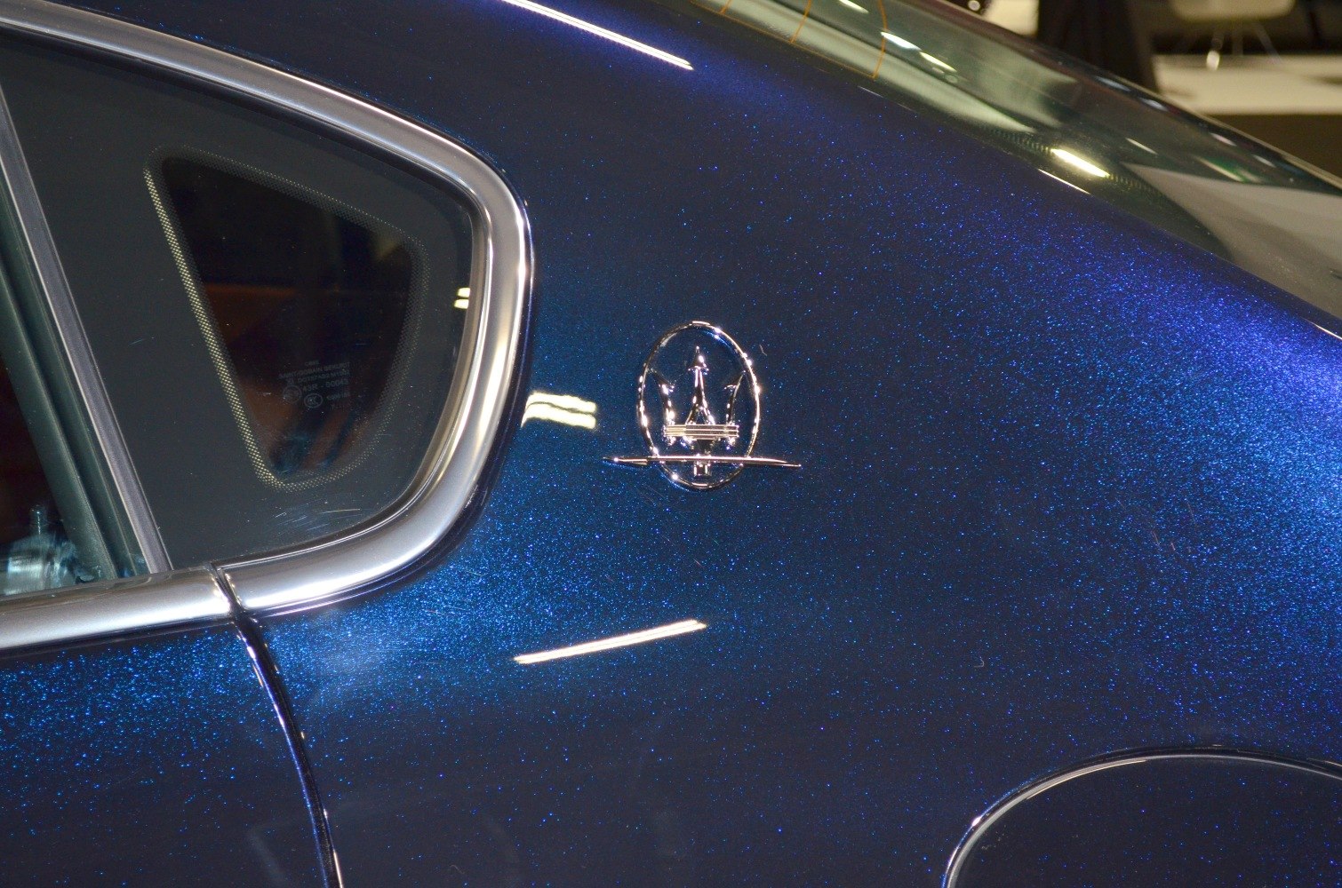 Close-up of side window trim and emblem on metallic paint