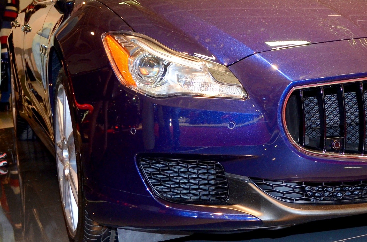 Close-up of front headlight and grille with mesh pattern on luxury sedan