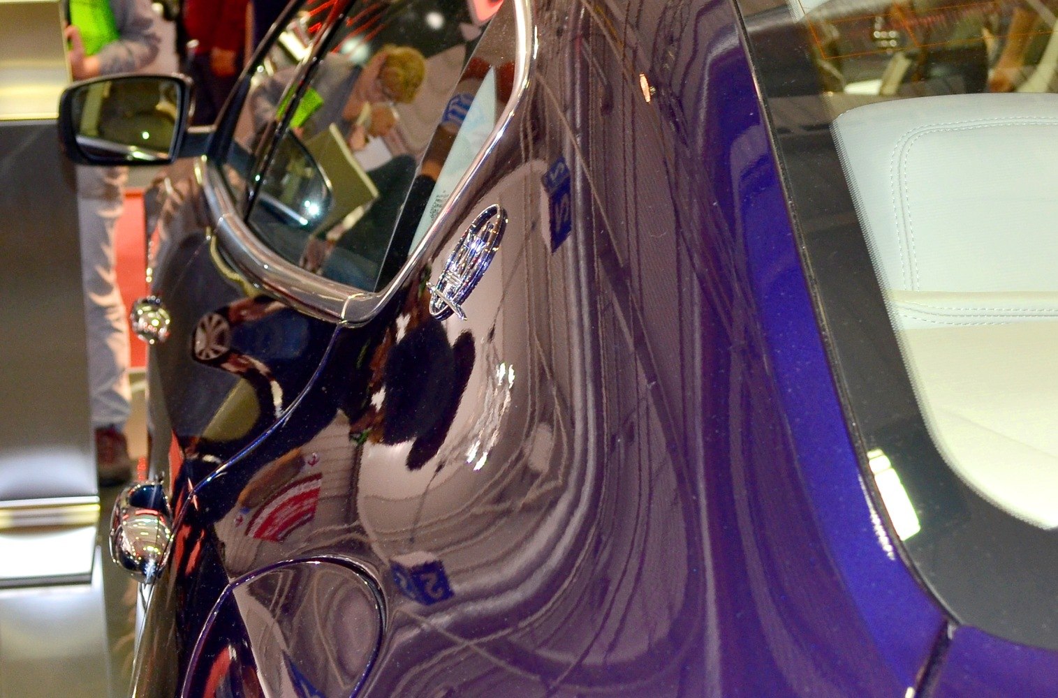 Close-up of dark blue sedan side with badge emblem and door handle