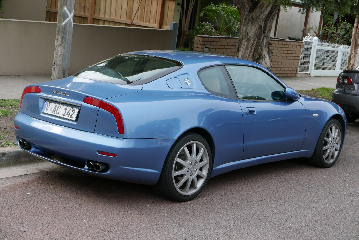 Rear and side view of a blue sports coupe with distinctive tail lights and quad exhausts