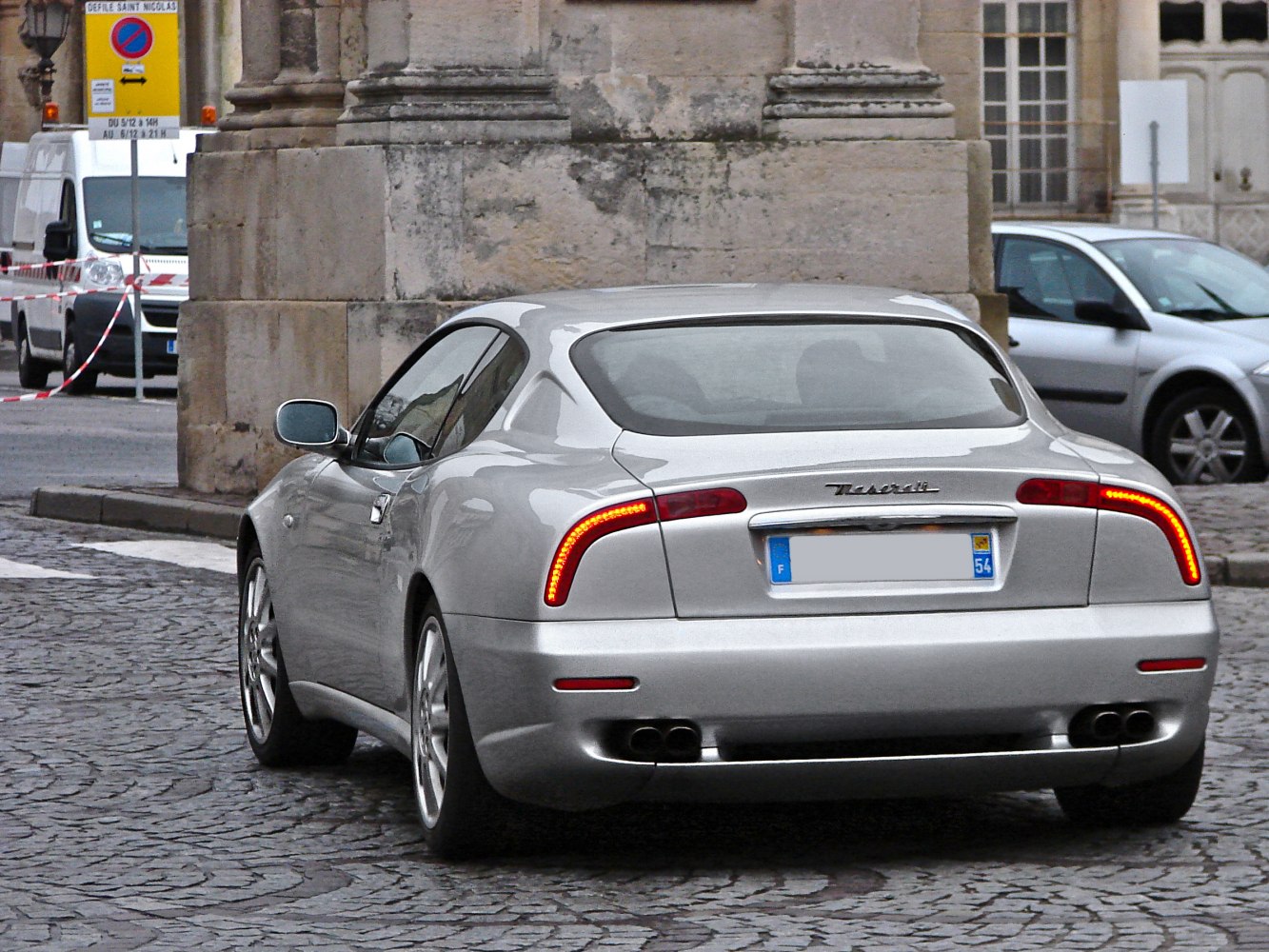 Silver sports coupe rear with LED taillights and dual exhausts on cobbled street