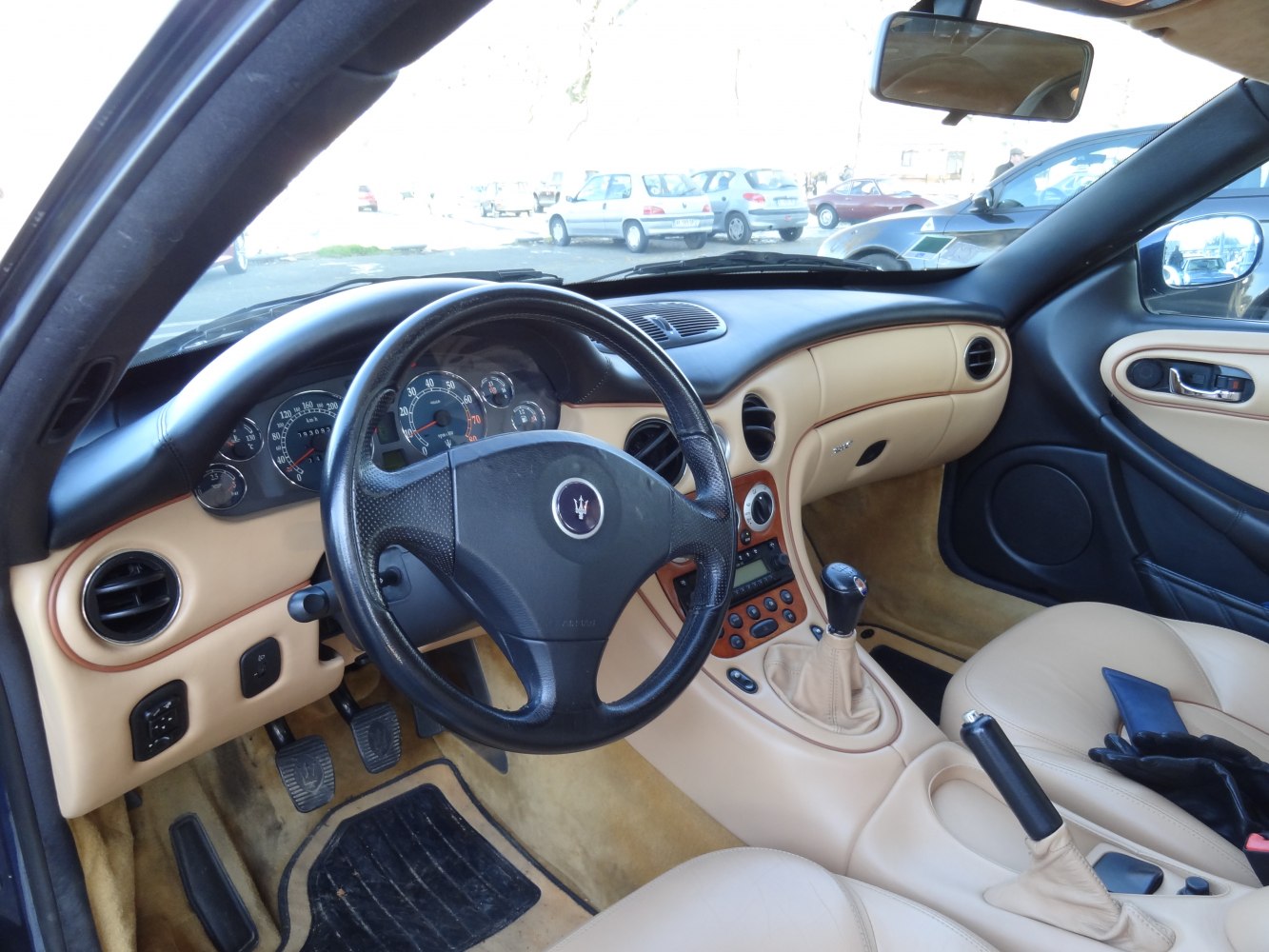 Beige luxury interior with black steering wheel and manual gear shift
