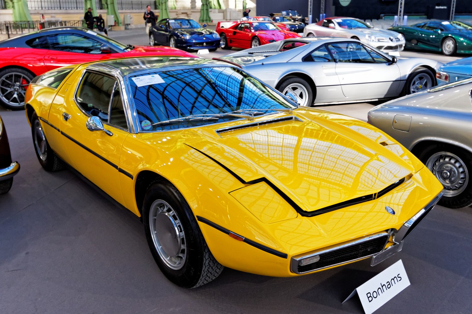 Yellow wedge-shaped sports coupe with pop-up headlights and chrome window trim