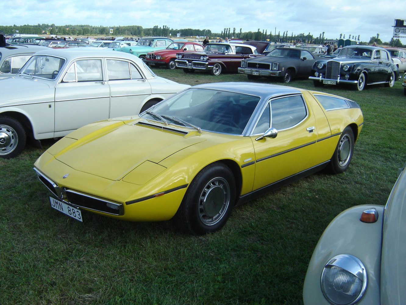 Yellow mid-engined sports coupe with pop-up headlights and sleek low-profile design