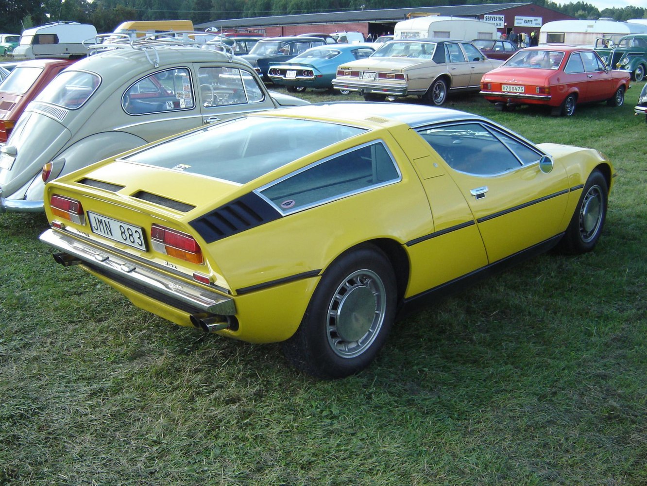 Yellow mid-engine sports coupe with distinctive rear design and chrome bumper.