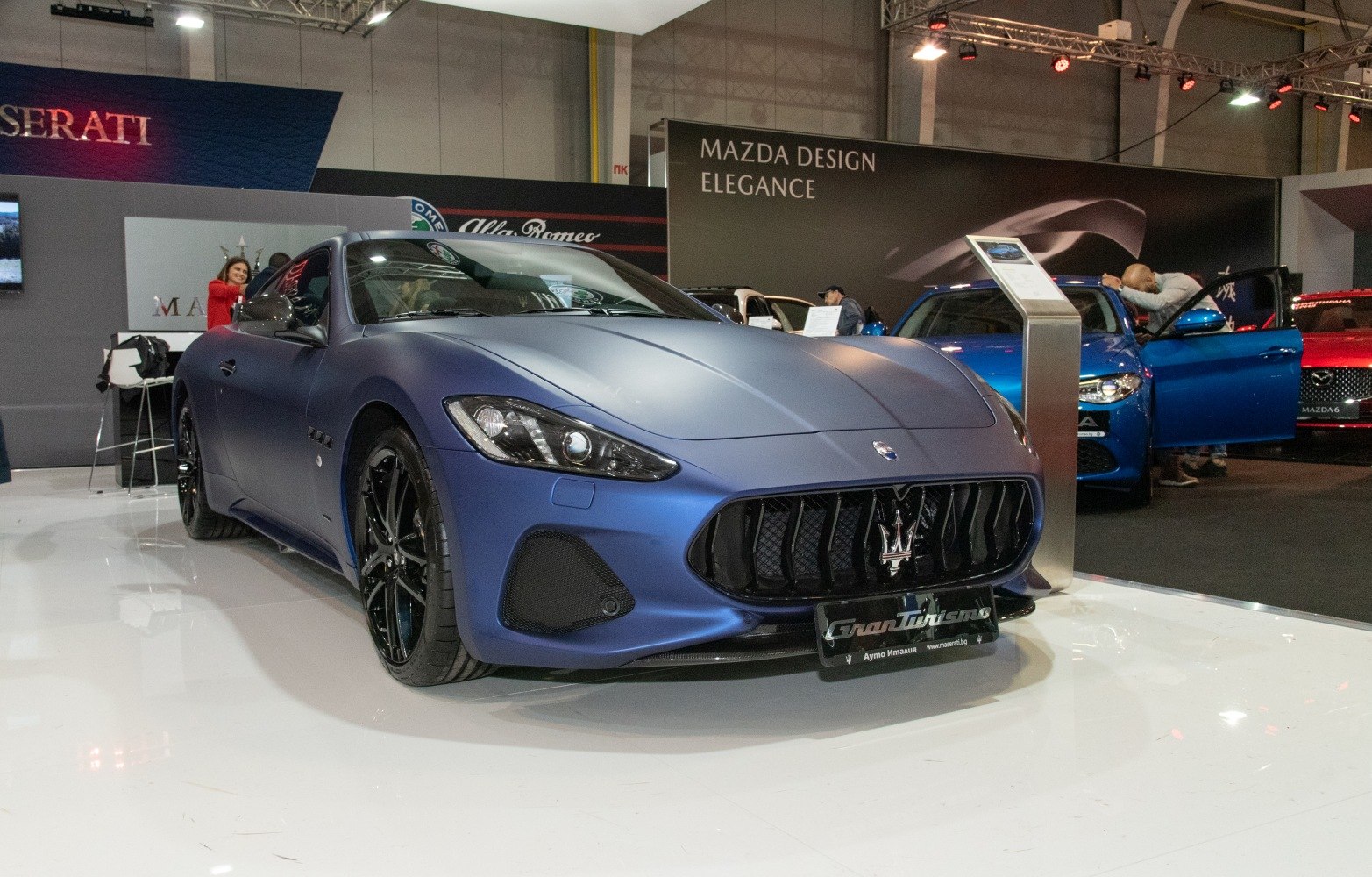 Matte blue coupe with aggressive grille and black multi-spoke wheels.
