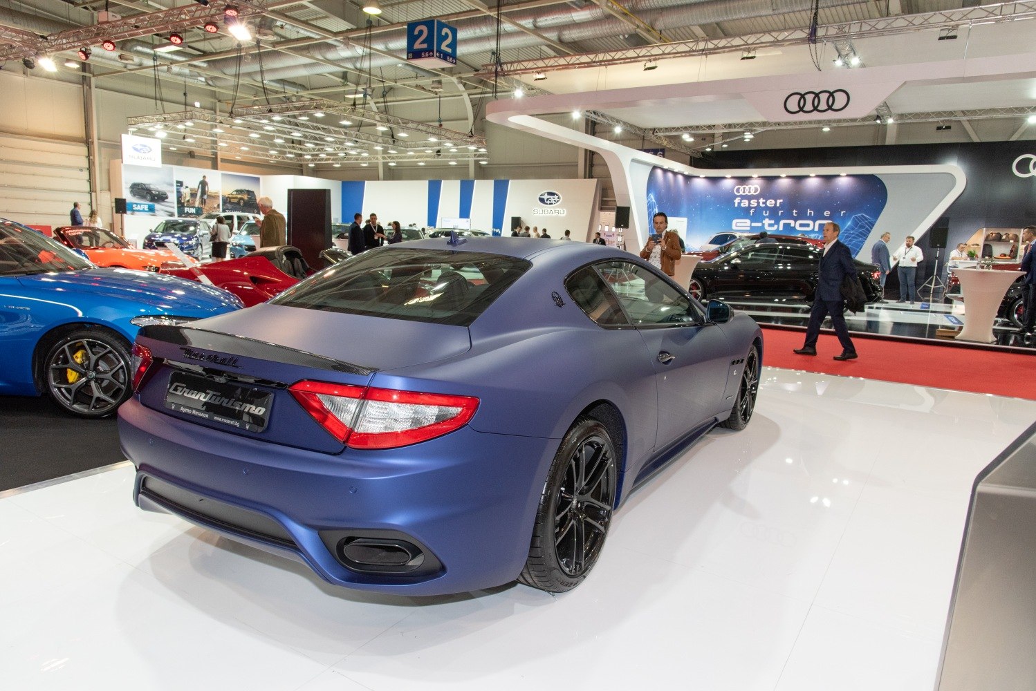 Rear side view of a matte blue luxury coupe with black wheels