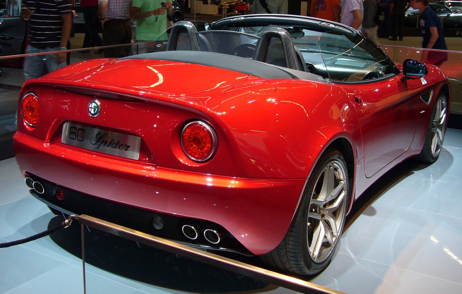 Rear view of a red convertible showcasing round taillights and quad exhaust pipes