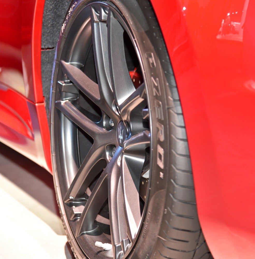 Matte black 10-spoke alloy wheel with Pirelli P Zero tire on red paint.