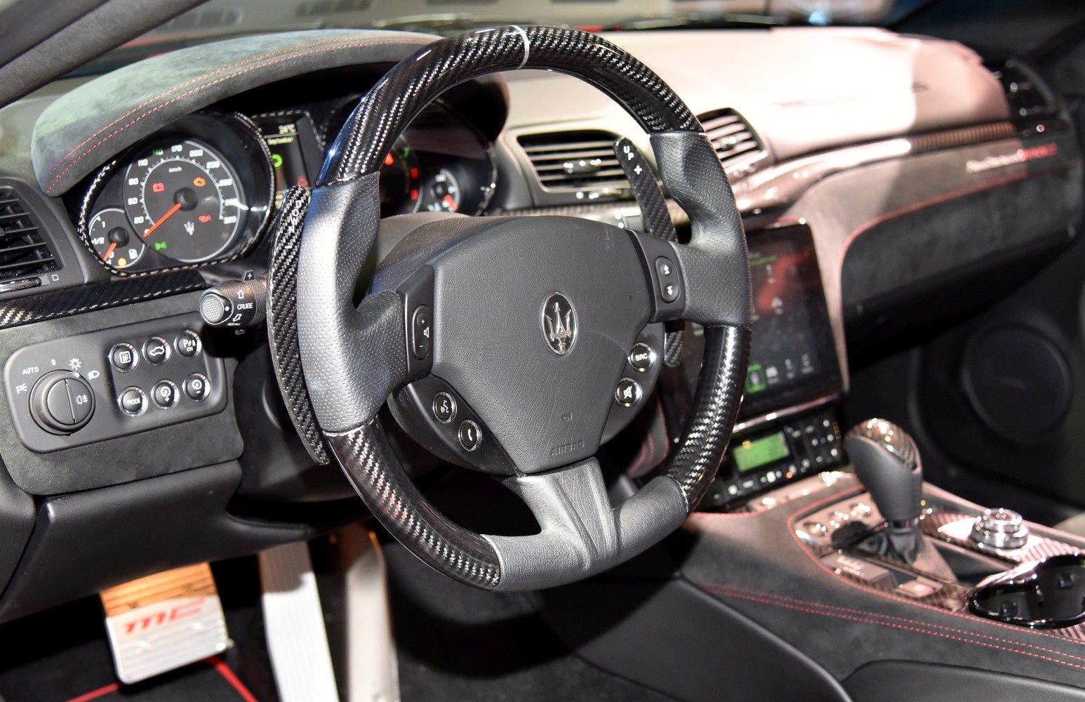 Carbon fiber steering wheel and detailed dashboard with red stitching.