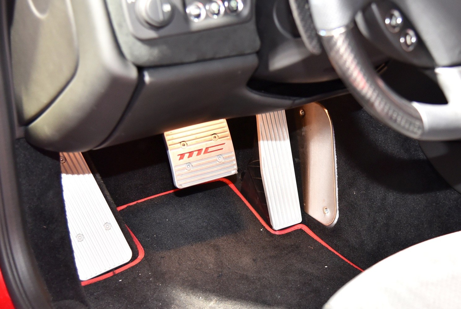 Pedal set with branded footrest and accelerator pedals inside a luxury sports car