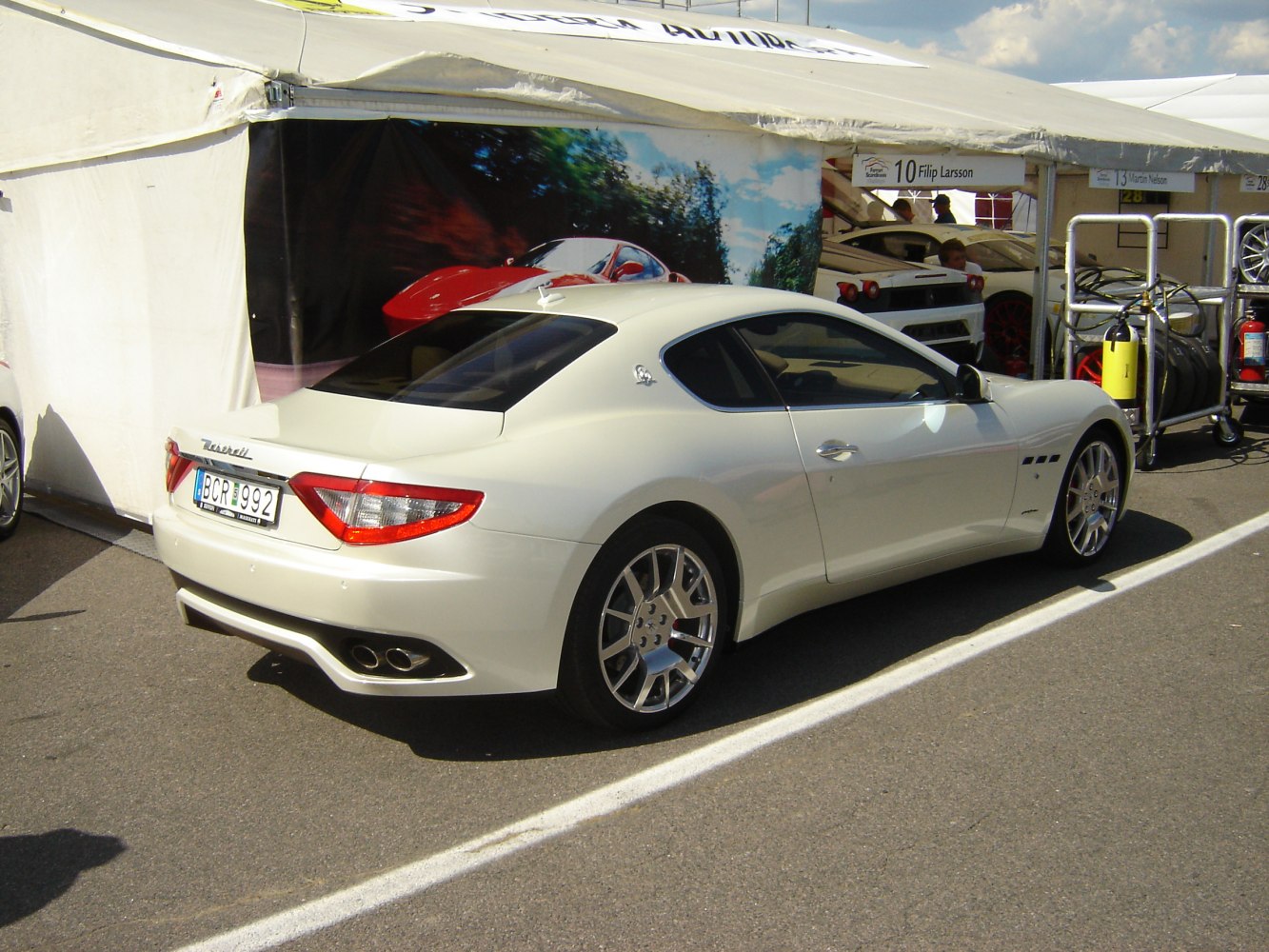 White sporty coupe rear-side view with quad exhaust and taillights