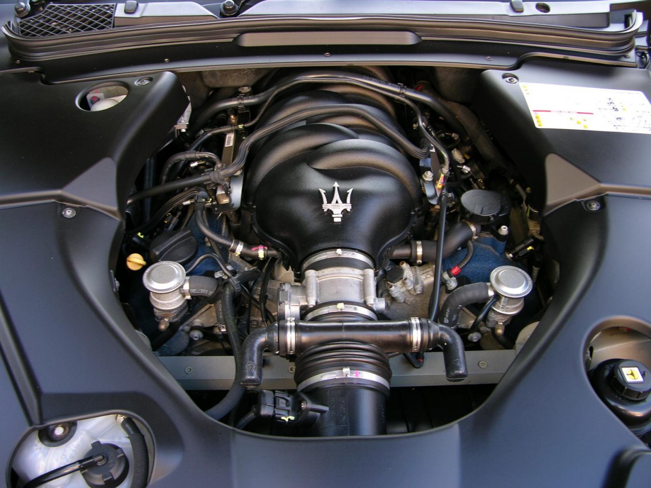 Detailed view of a Maserati engine bay with emblem and components