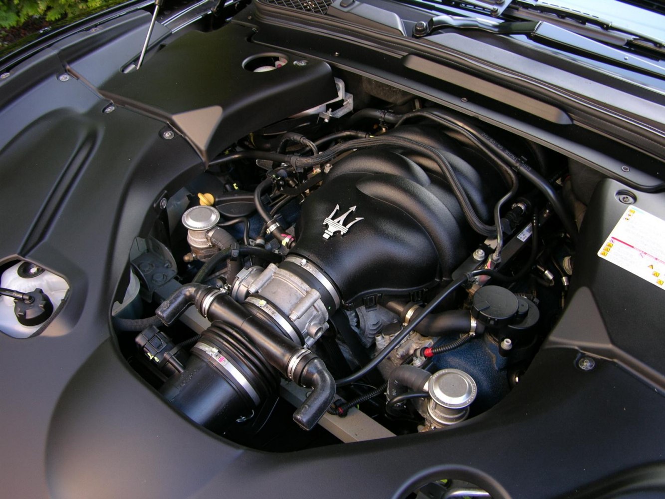 Engine bay with black intake manifold and Maserati trident logo