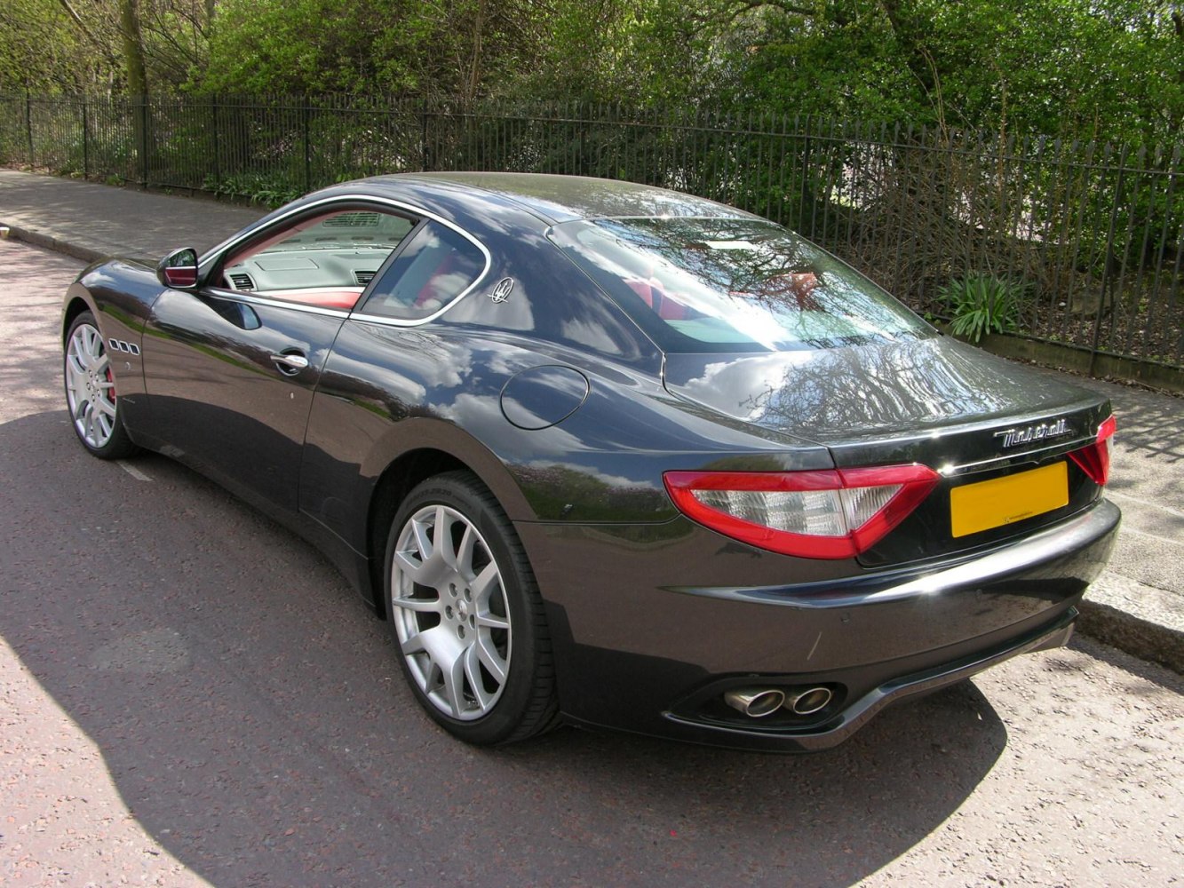 Rear-side view of luxury sports coupe with dual exhaust and curved rear window