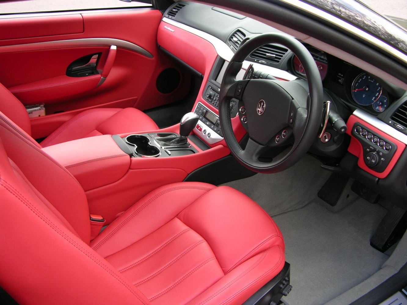 Red leather luxury car interior with detailed dashboard and steering wheel