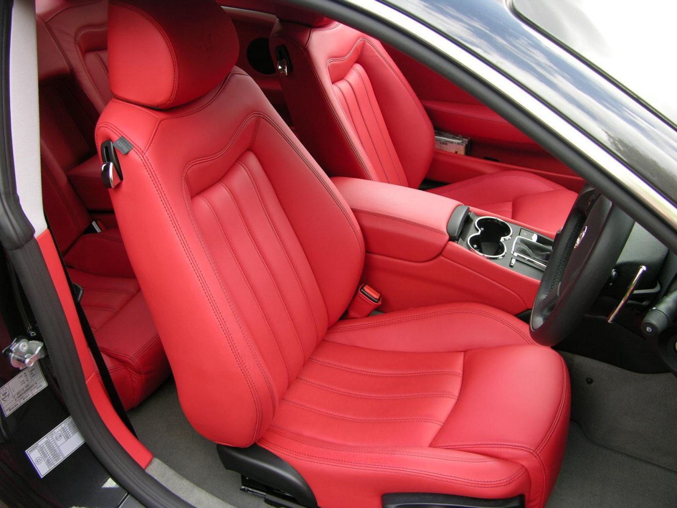 Red leather bucket seats with detailed stitching and center console cup holders.