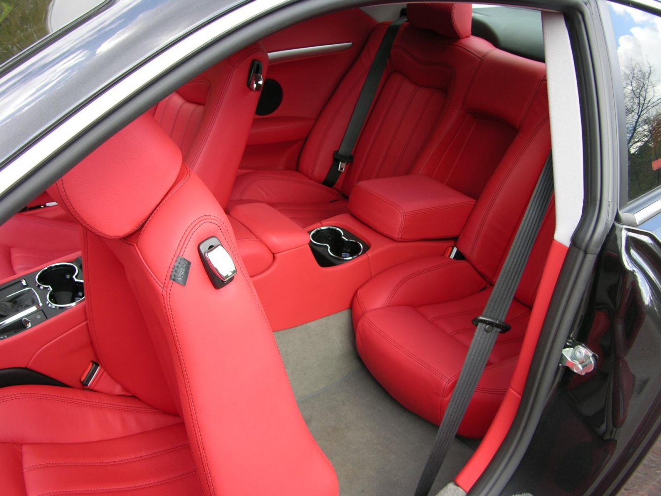 Luxury red leather car interior with detailed stitching and cup holders