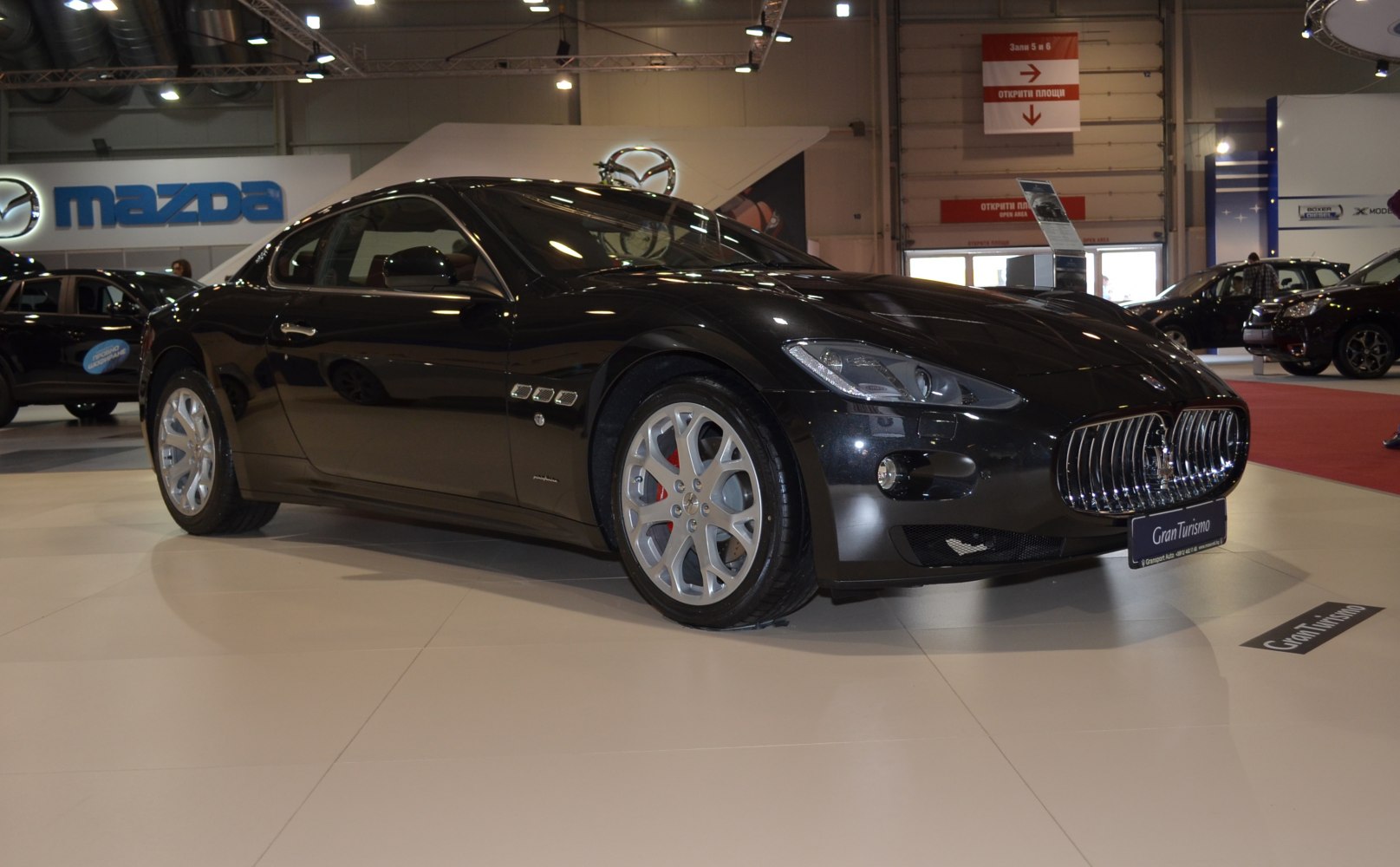 Black luxury coupe with prominent grille and alloy wheels in showroom.