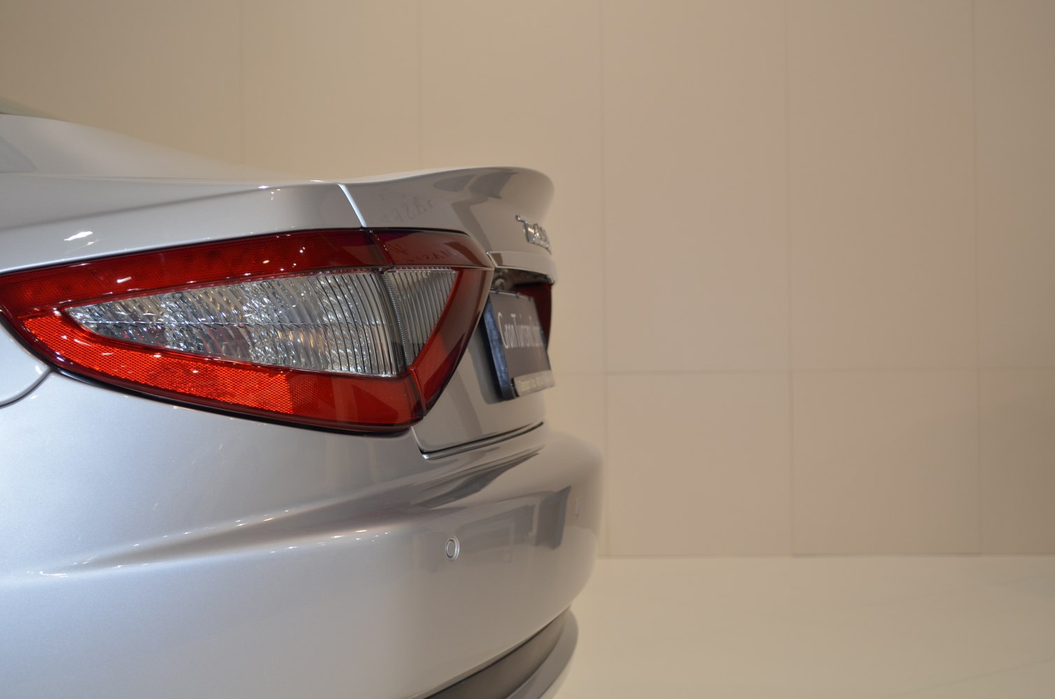 Close-up of rear taillight and trunk spoiler on a sleek silver vehicle.